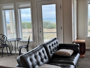 Relax in this inviting living area with a sofa, table, and chair, offering a serene view of the coastal landscape.