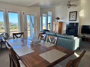 A dining area with a wooden table and chairs, a sofa, a fireplace, and a television.