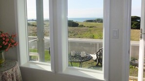 Ein Zimmer mit großem Fenster und Blick auf eine grüne Landschaft sowie das Meer.