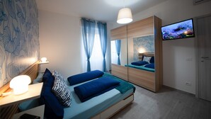 Un dormitorio moderno con cama, mesita de noche y televisión montada en la pared.
