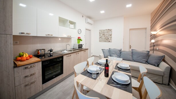 Una cocina moderna con comedor, armarios blancos y un sofá.