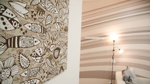 Una habitación con una pared a rayas, una lámpara de pie y un tapiz decorativo.