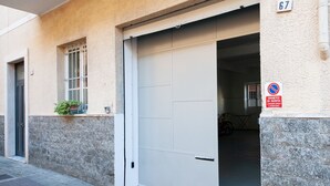 Un edificio con una puerta cerrada, una ventana con rejas y un letrero de no estacionamiento.