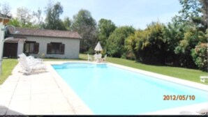 A swimming pool with a white building in the background. - Inviting 6-Bed Farmhouse (Cravans)