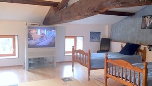 A bedroom with a bed, a television, and a wooden ceiling beam. - Inviting 6-Bed Farmhouse (Cravans)