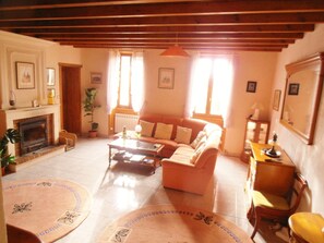 A cozy living room with a fireplace, a sofa, a coffee table, and a dining table. - Inviting 6-Bed Farmhouse (Cravans)