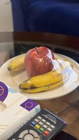 Un plato con una banana y una manzana sobre una mesa de vidrio.