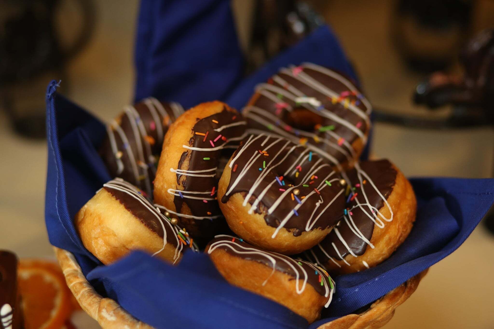 A basket of chocolate-dipped donuts with sprinkles.