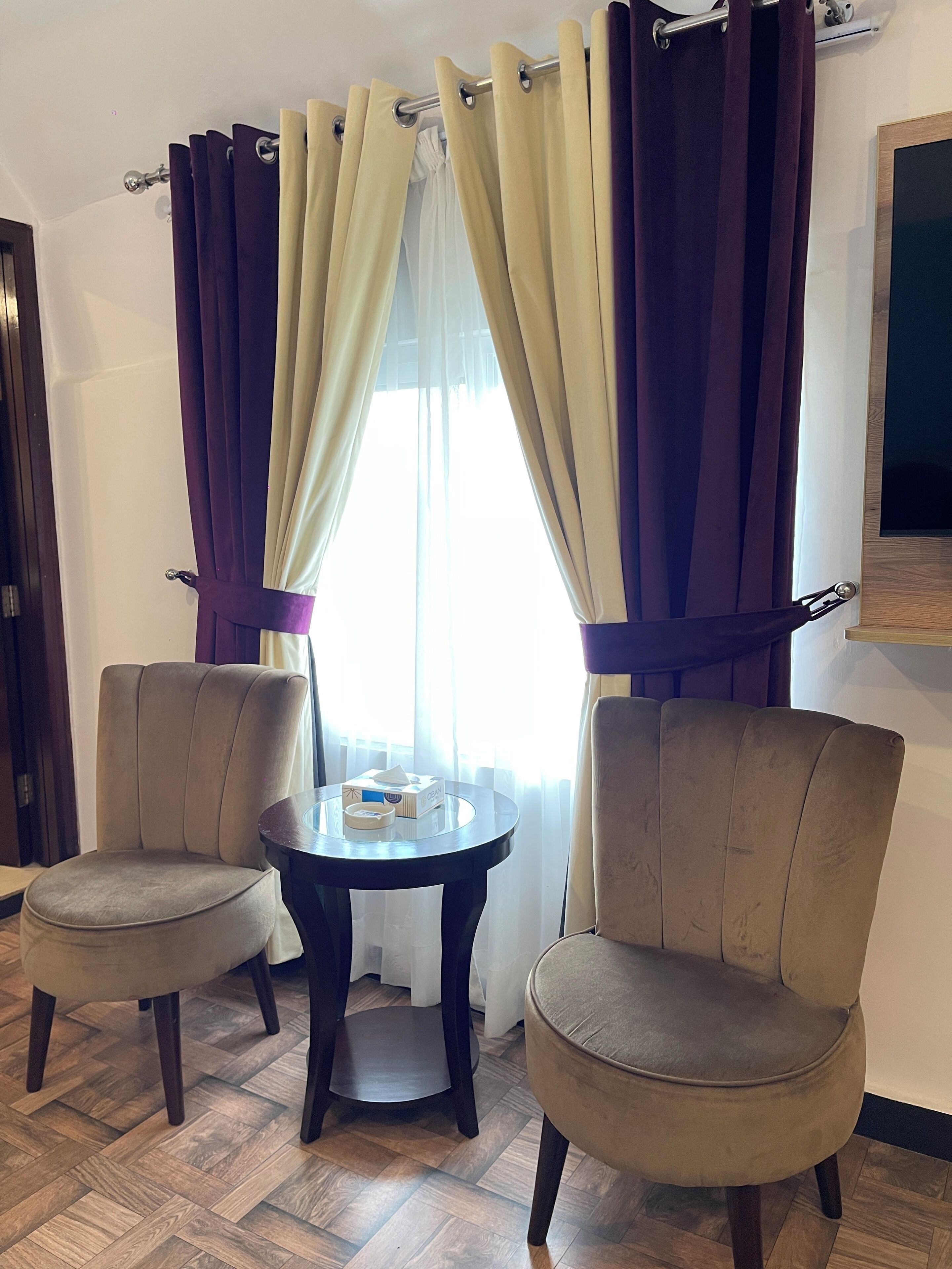 A room with two armchairs, a small table, and a window with curtains.