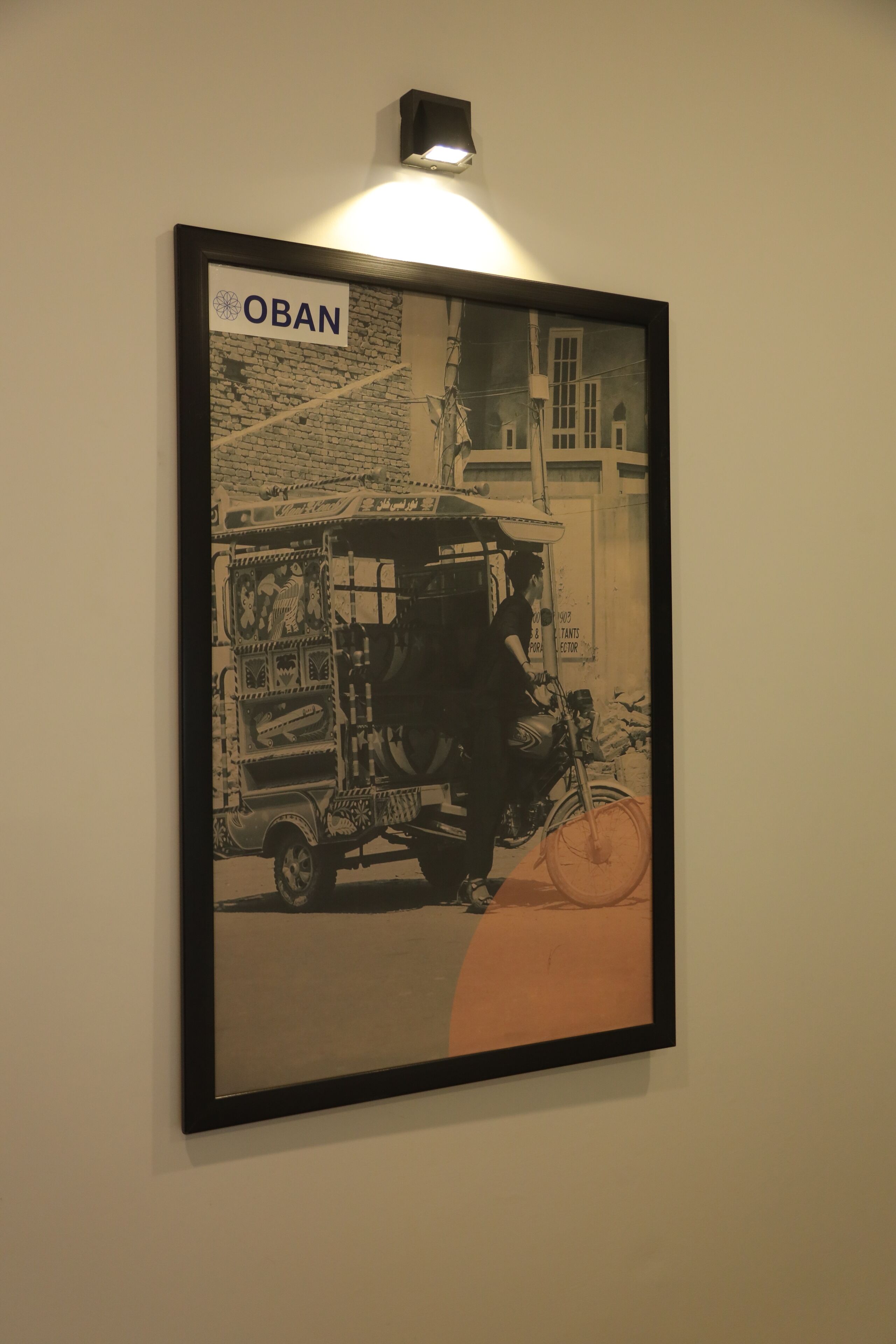 Une photographie en noir et blanc, encadrée, représentant une scène de rue avec une enseigne indiquant « OBAN » au-dessus.
