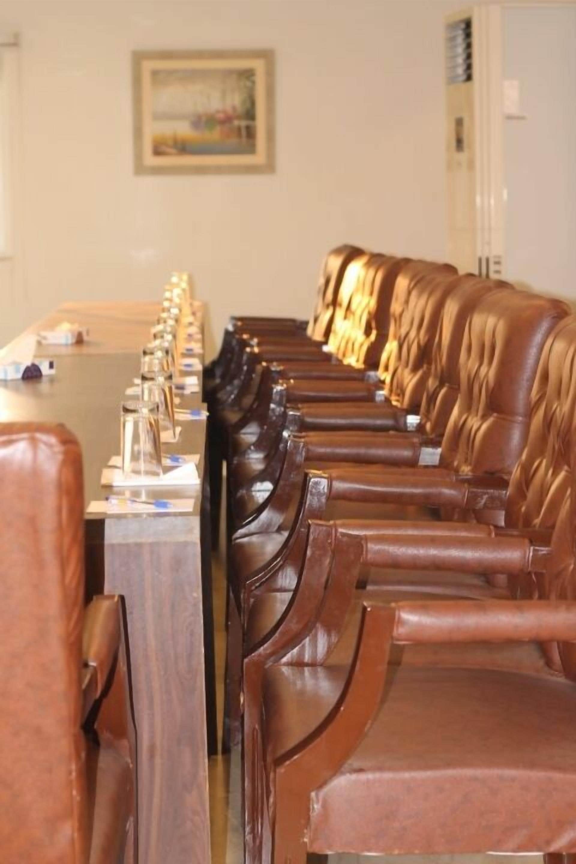 A conference room with rows of wooden chairs and a long table with water bottles and glasses.