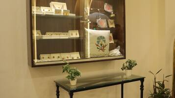 A display case labeled "SOUVENIRS" with various items inside, a small table with potted plants, and a polished black floor.