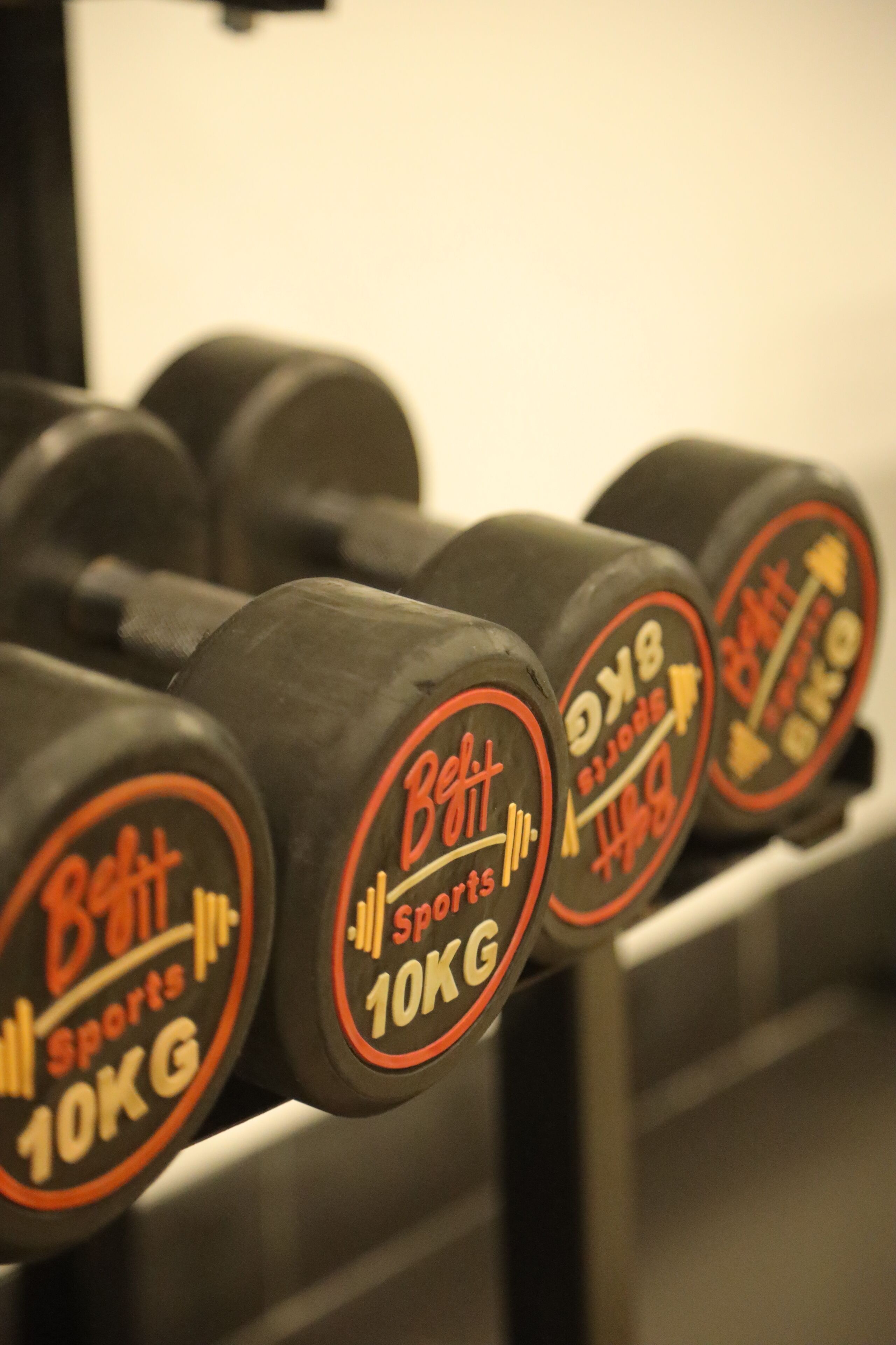 A set of 10KG dumbbells with the brand name 'Beit Sports' on a rack.