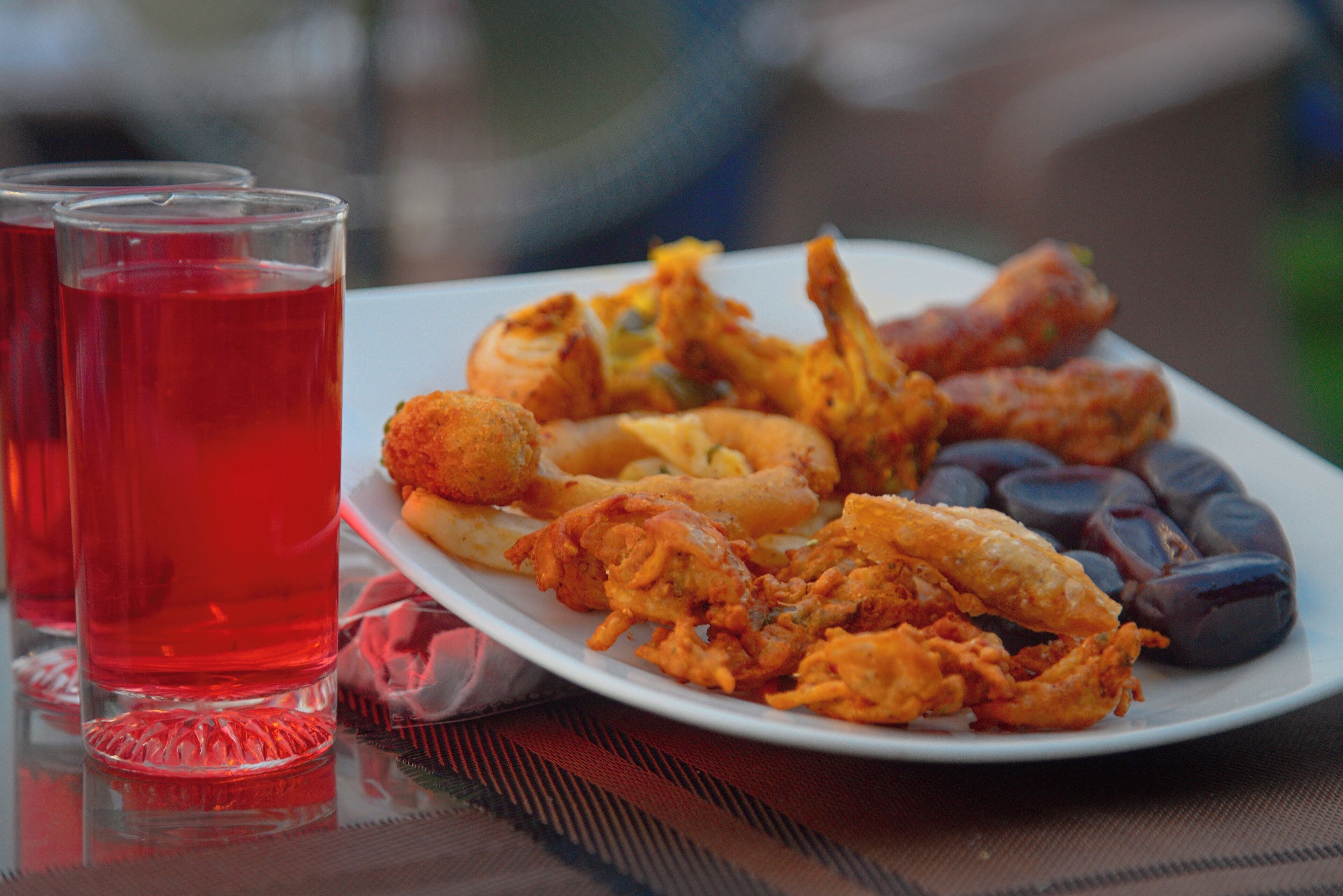 A plate of fried seafood and a glass of red beverage on a table.