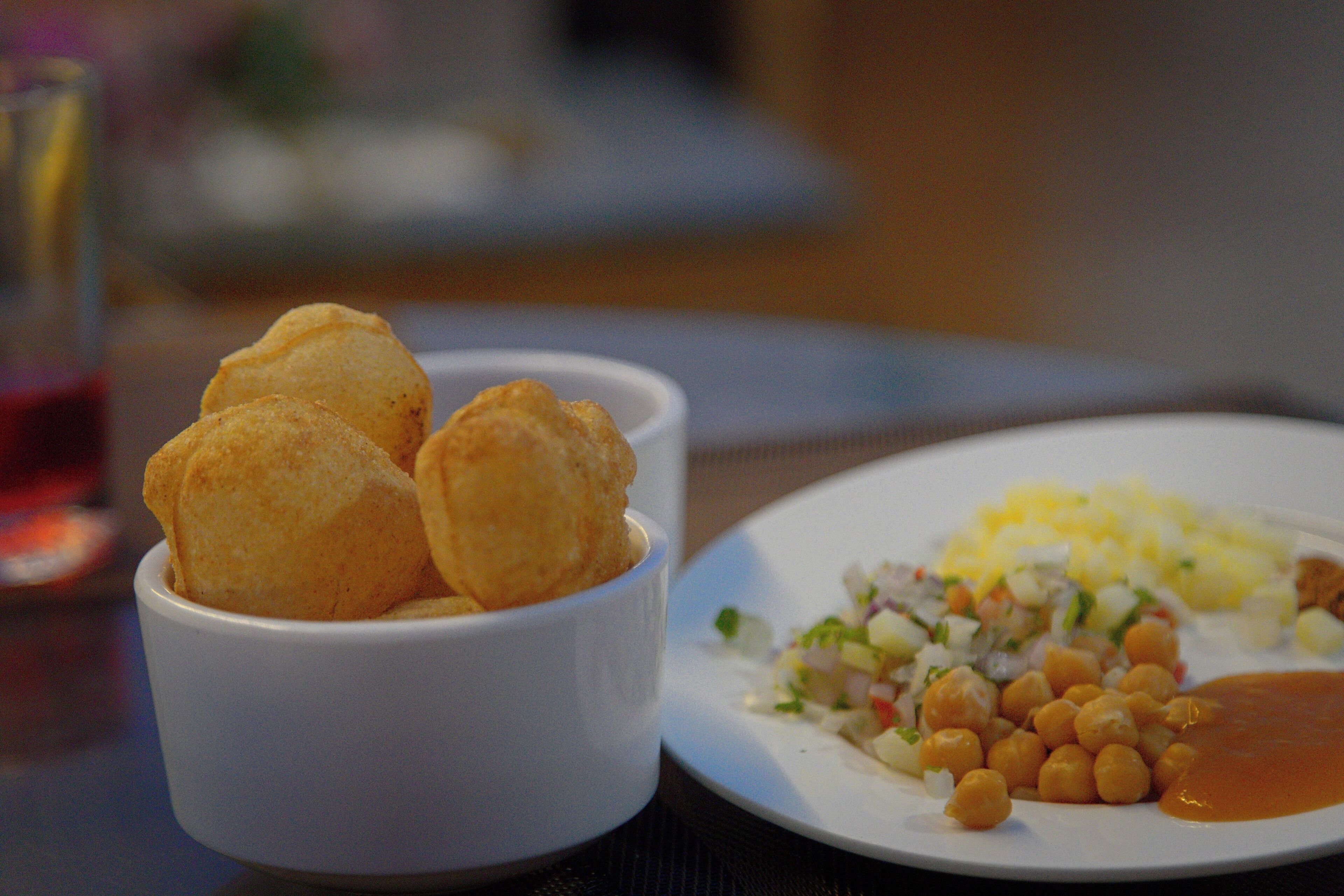A plate with a salad, chickpeas, and a small bowl of fried items.