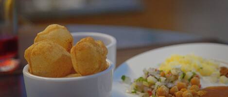 A plate with a salad, chickpeas, and a small bowl of fried items.