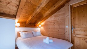 A wooden-paneled room with a bed, two bedside lamps, and a wooden door.