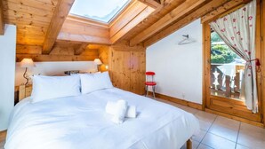 A wooden room with a bed, a skylight, and a sliding glass door to the outside.