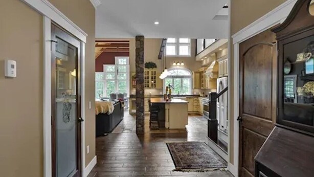 A spacious kitchen with a central island, wooden flooring, and a view into the dining area. - Peaceful Mountain Oasis (Woodstock)