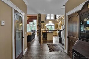A spacious kitchen with a central island, wooden flooring, and a view into the dining area.
