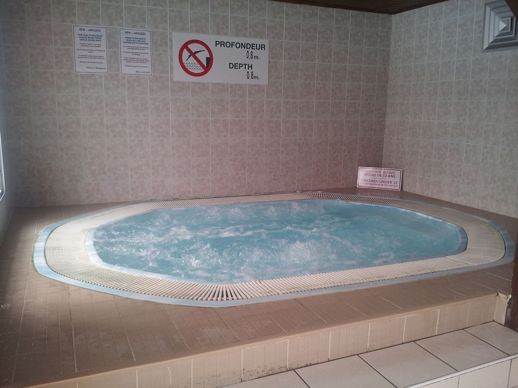 Een kuip met warm water, een betegelde wand en borden met informatie over de diepte en het duikverbod.