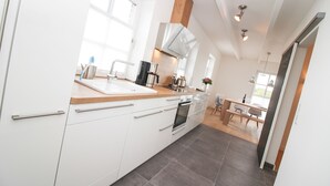 Eine moderne Küche mit weißen Schränken, einer Holz Arbeitsplatte und einem eingebauten Ofen.