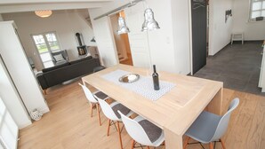 Ein moderner Essbereich mit Holztisch, weißen Stühlen und Pendelleuchten.