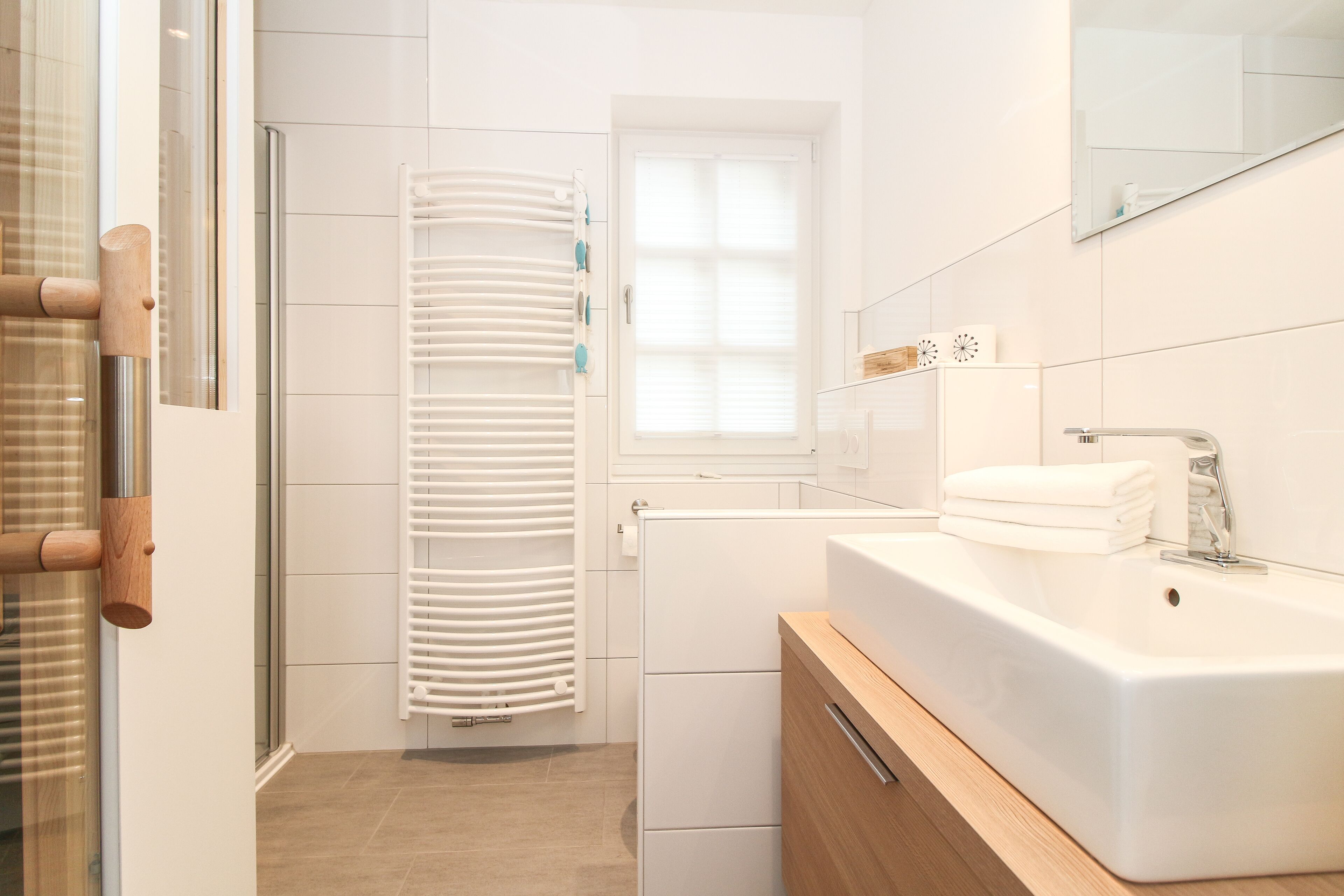 Un baño moderno con lavamanos, espejo y toallero blancos.