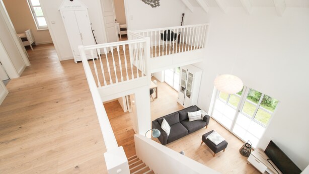 Ein geräumiges Loft mit hoher Decke, einem Balkon, einem Essbereich und einem Wohnzimmer mit Sofa und Fernseher.
