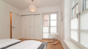 Ein Schlafzimmer mit einem Bett, einem Schaukelstuhl, einem Fenster mit Jalousien und einer Tür.