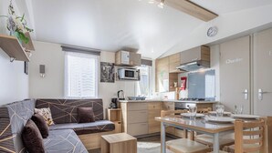 Ein kompakter Wohnbereich mit Sofa, Esstisch und Stühlen, einer Küchenzeile und einer Mikrowelle.