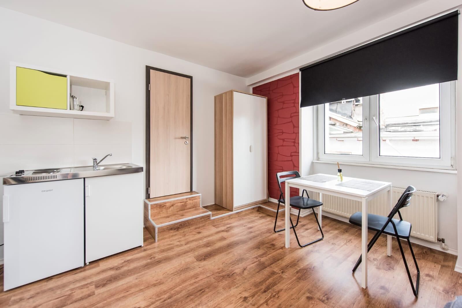 Una cocina compacta con lavamanos, armarios y una zona de comedor con mesa y sillas.