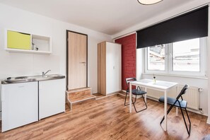 A compact kitchen with a sink, cabinets, and a dining area with a table and chairs. - Pension Michelangelo (Eisenach)