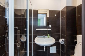 A modern bathroom with a glass shower enclosure, a white sink, and a toilet. - Pension Michelangelo (Eisenach)