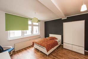 A bedroom with a bed, a radiator, a window with blinds, a wardrobe, and a hanging light fixture. - Pension Michelangelo (Eisenach)