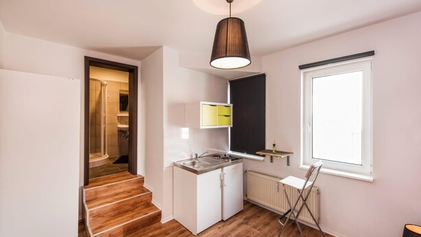 A compact kitchen with a built-in stove, a small window, and a radiator. - Pension Michelangelo (Eisenach)