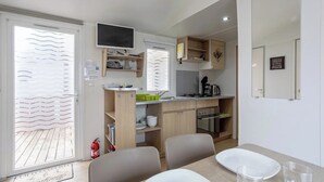 Una cocina compacta con comedor, un televisor sobre la encimera y un extintor cerca de la puerta.