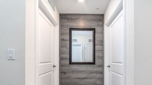 A hallway with two white doors, a wooden accent wall, and a tiled floor.