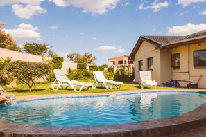A swimming pool with lounge chairs, a house, and a clear sky. - the oak cabin (Bulawayo South)