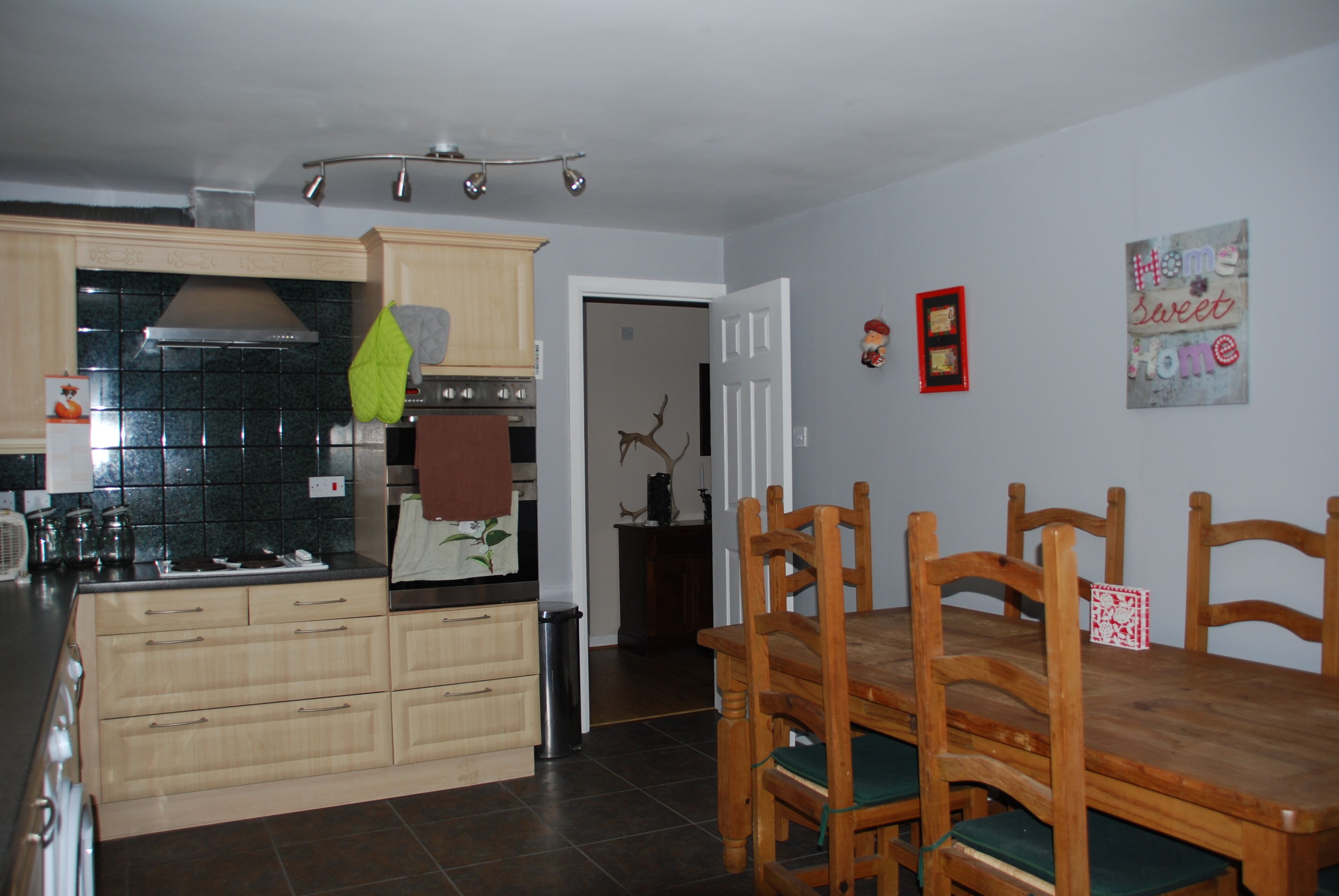 A kitchen with wooden cabinets, a stove, and a dining area with a wooden table and chairs.