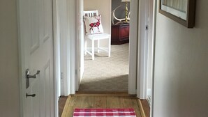 Ein Flur mit einem Schachbrettmuster-Teppich, einem weißen Stuhl mit einem Rentierkissen und einer Wand mit Herzdekorationen.