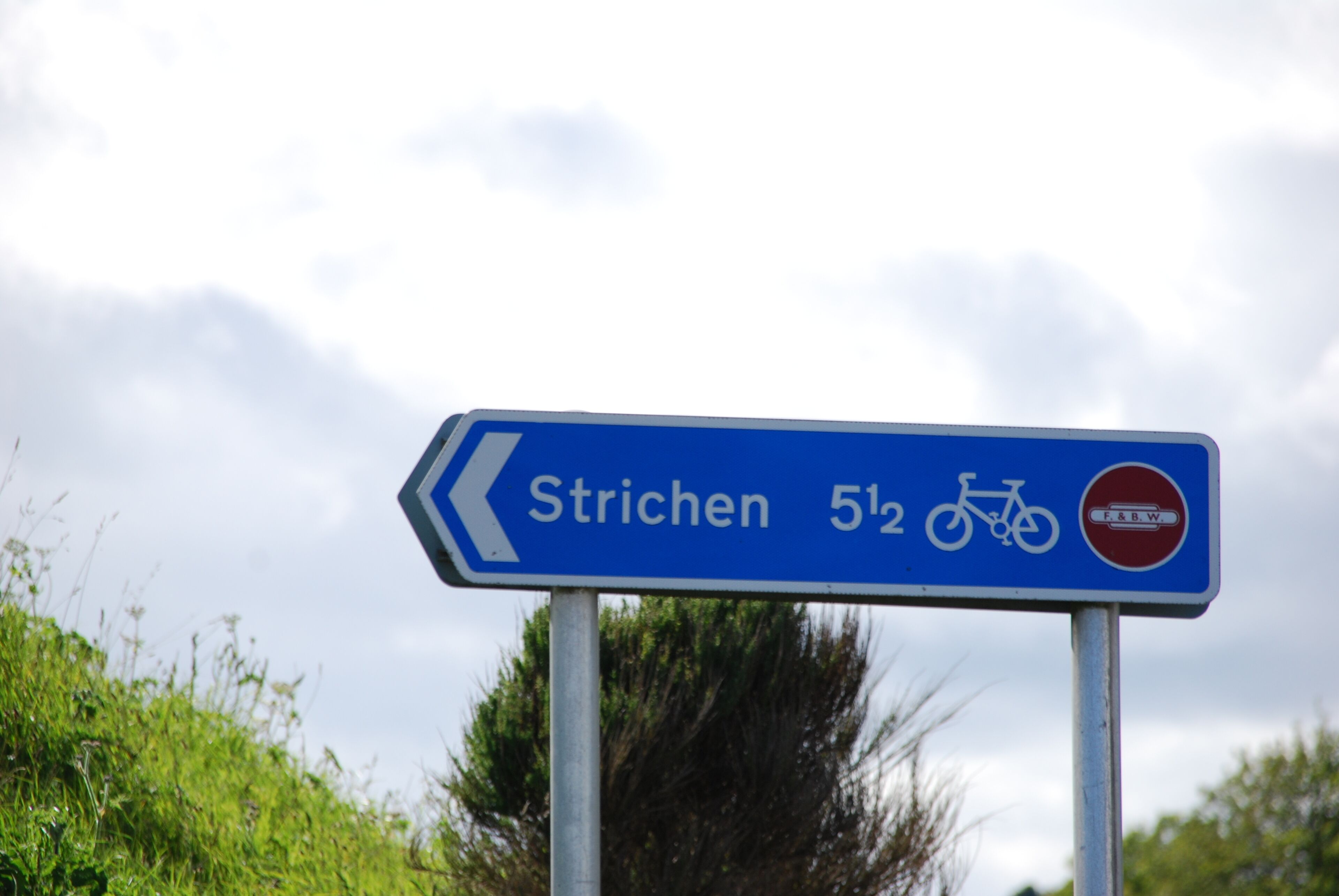 Ein Wegweiser nach Strichen mit Fahrradsymbol und Entfernungsangabe.