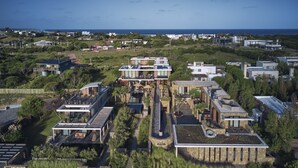Un barrio residencial moderno con varias casas, un camino central y vista al océano.