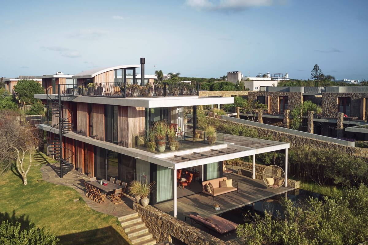 Una casa moderna de varios pisos con terraza en la azotea, zona de estar al aire libre y escalera de caracol.