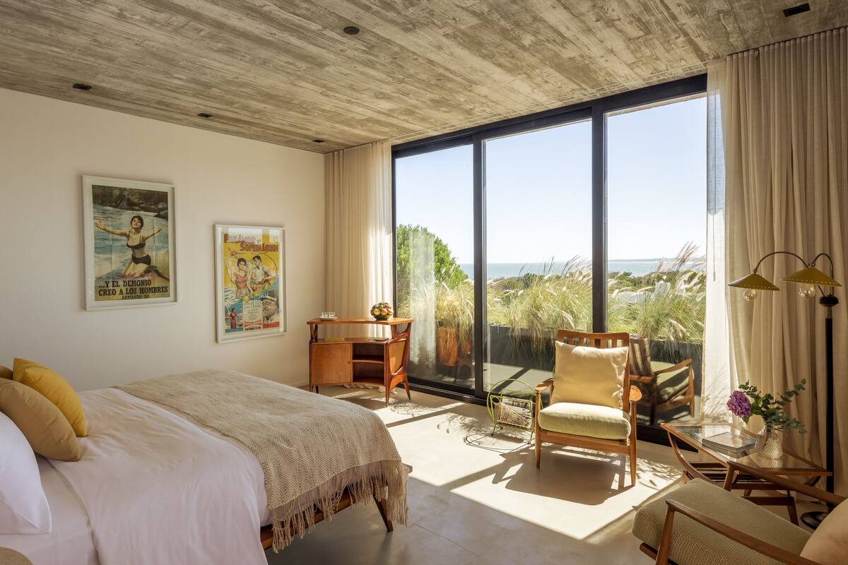 Un dormitorio con una cama grande, un escritorio, una silla y vistas al océano.