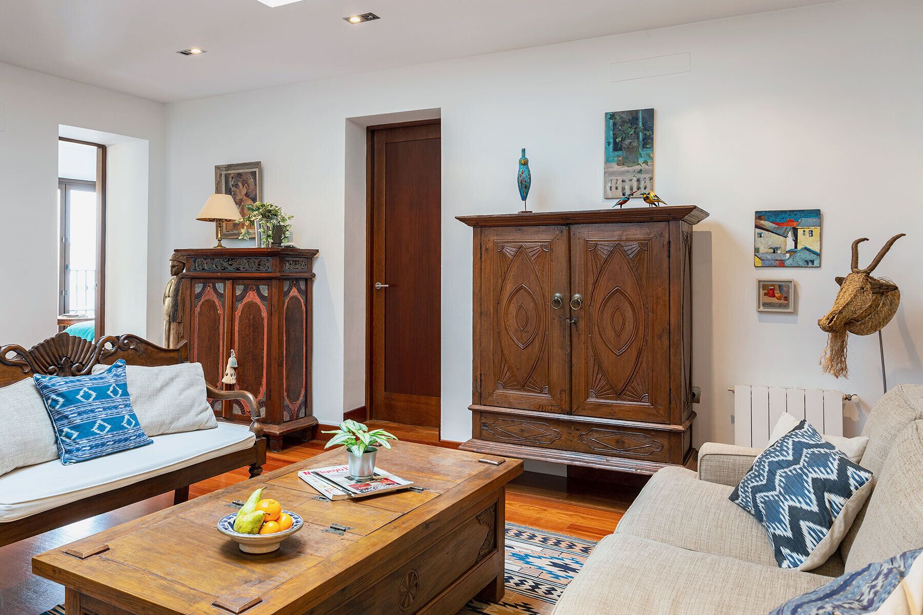 A living room with a sofa, coffee table, wooden cabinet, and artwork on the walls.