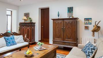 A living room with a sofa, coffee table, wooden cabinet, and artwork on the walls.