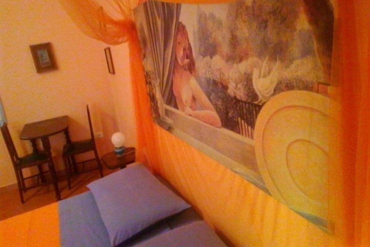 Una habitación con una cama, una mesita y una silla.