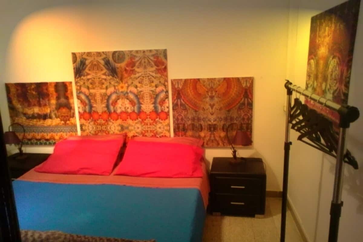 Un dormitorio con cama, dos mesitas de noche y una lámpara.