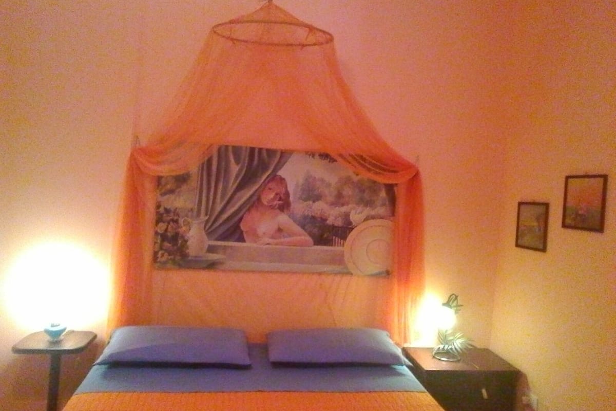 Una habitación con una cama, una mesita de noche, una lámpara y un cuadro en la pared.